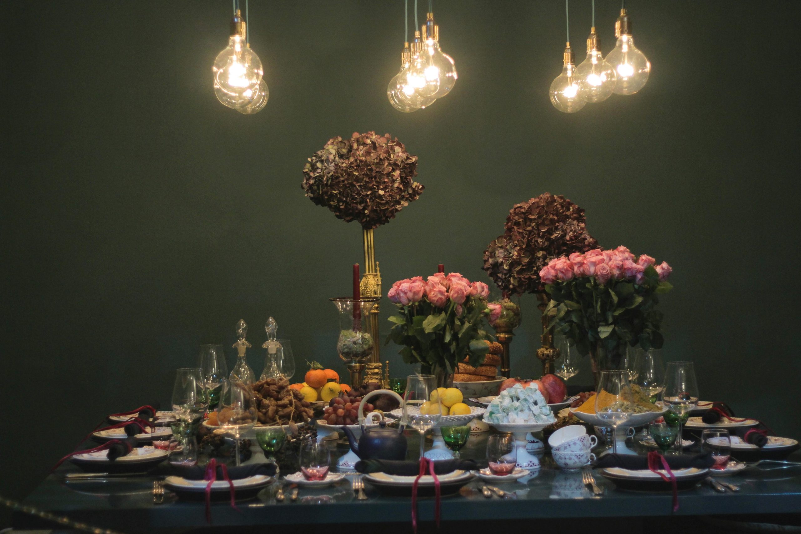 Party set up with flowers and food in front of a dark green background
